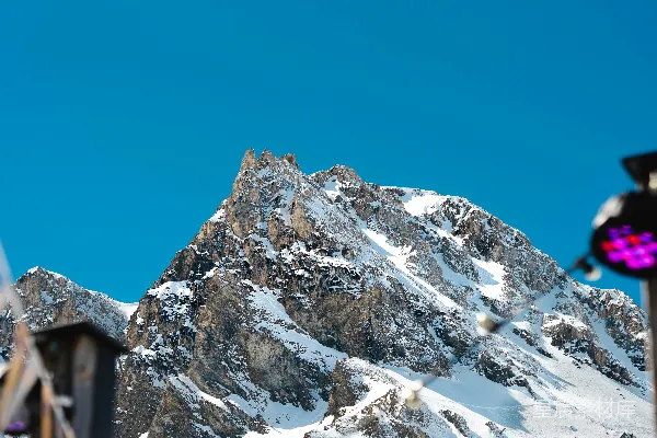 高清摄影 一座被雪覆盖的山峰，前面有一个钟楼。