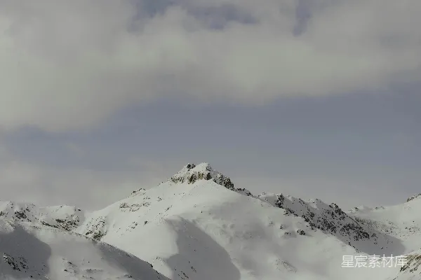 高清摄影 一座被白雪覆盖的山峰在多云的天空下