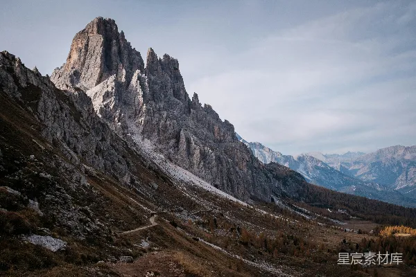 高清摄影 陡峭的山峰矗立在干燥的草地上方。