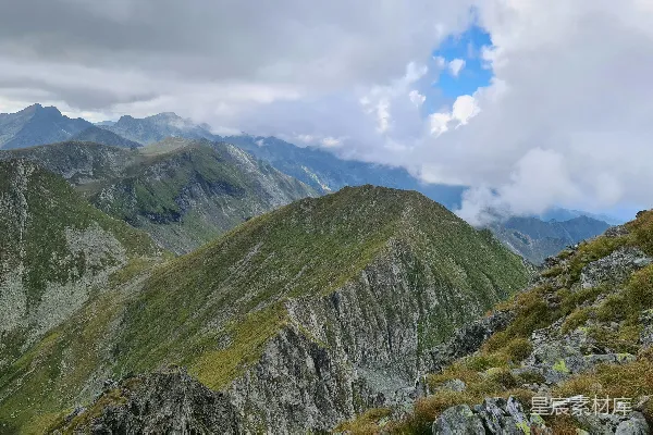 高清摄影 一个男人站在山顶上，旁边是郁郁葱葱的山坡。