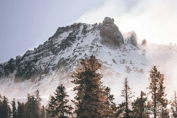 高清摄影 一座被雪覆盖的山，周围环绕着树木。