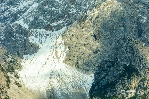 高清摄影 巍峨的岩石山峰，山上有积雪和绿树。
