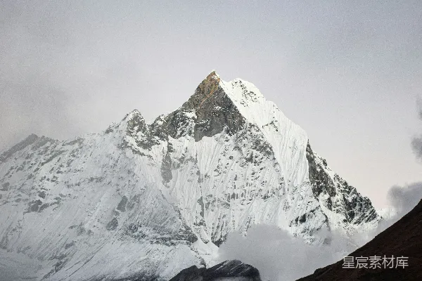 高清摄影 阴云密布的天空下，覆盖着积雪和云雾的山峦