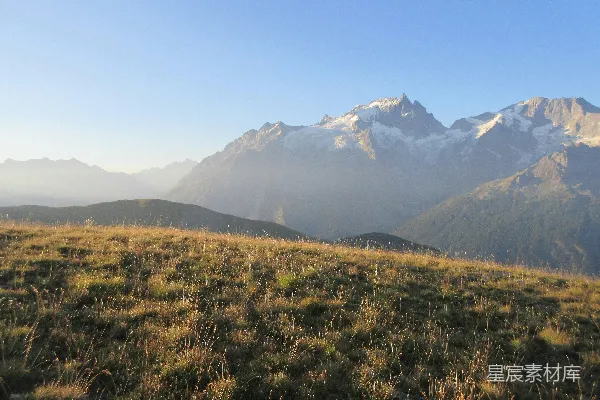 高清摄影 草地上前景，远处有雾气缭绕的山峦
