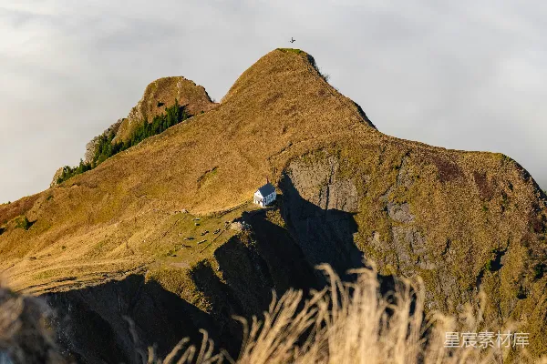 高清摄影 一座白色的小屋坐落在草地上方的山顶上。