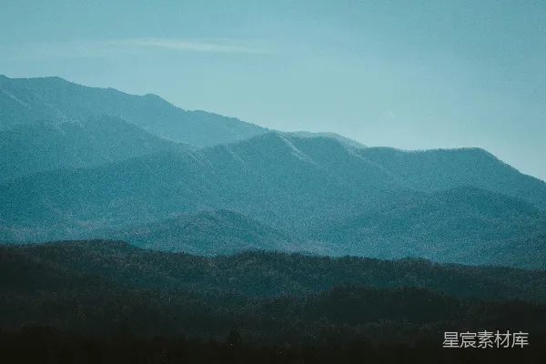 高清摄影 一座山脉的远景，前景中有树木。