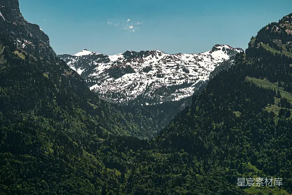 高清摄影 郁郁葱葱的山脉环绕着远处白雪覆盖的山峰。