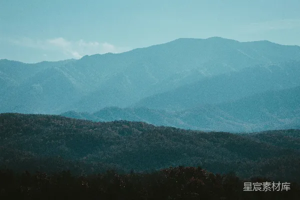 高清摄影 一幅山峦的景色，前景是树木。