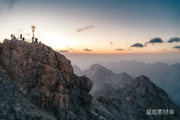 高清摄影 黄昏时分，徒步者在岩石山顶上