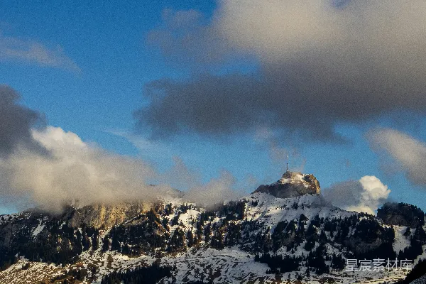 高清摄影 云层下的蓝色天空下，雪山覆盖着白雪。