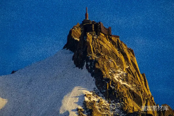 高清摄影 一座被雪覆盖的山峰，山顶有一座塔楼。