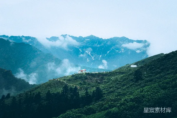 高清摄影 雾气缭绕的山峦，绿意盎然的山丘和散布其中的白色建筑。