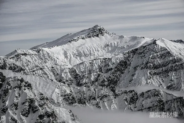 高清摄影 一座覆盖着积雪和云雾的山在蓝天映衬下
