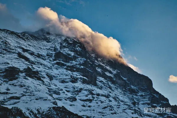 高清摄影 一座被雪和云覆盖的山峰，在蓝天之下