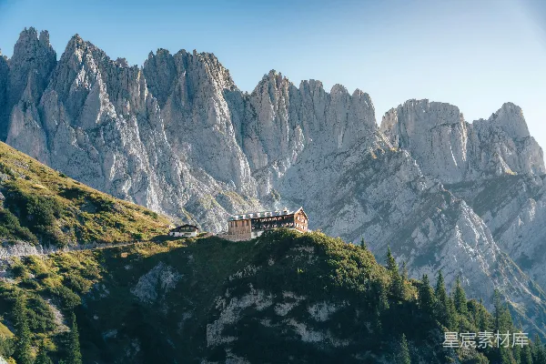 高清摄影 山间小屋坐落在绿坡之上，周围是尖峭的山峰。