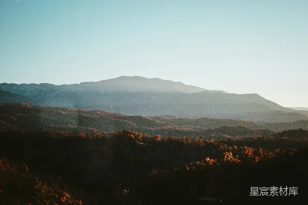 高清摄影 山峦远景，前景有树木。