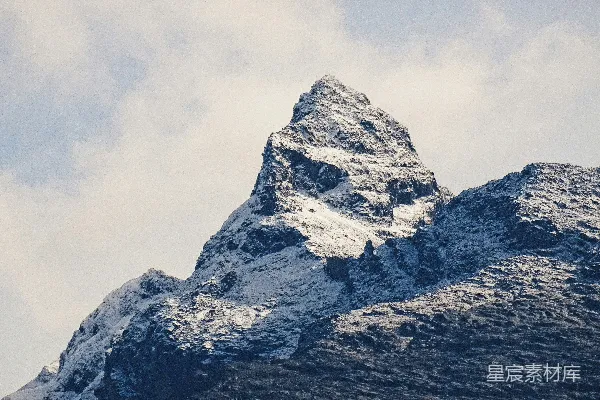 高清摄影 白天，云层密布的天空下覆盖着积雪的山峰。