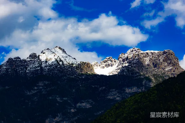 高清摄影 白雪覆盖的山峰在明亮的蓝天白云下。