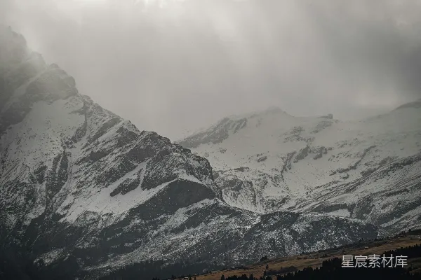 高清摄影 云层密布的天空下覆盖着积雪的山脉。