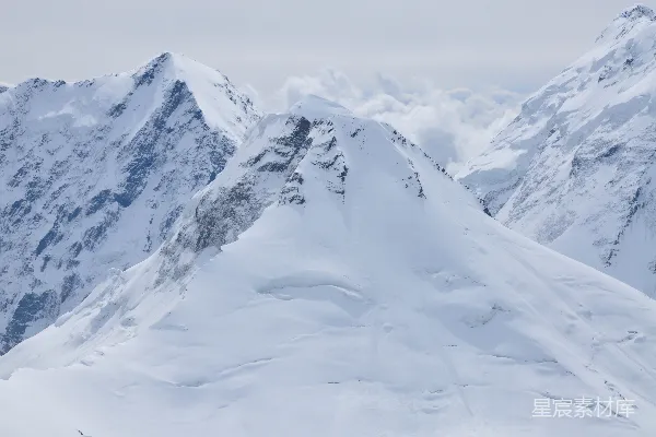 高清摄影 一座覆盖着积雪的山峰，山脚下有一片山谷。