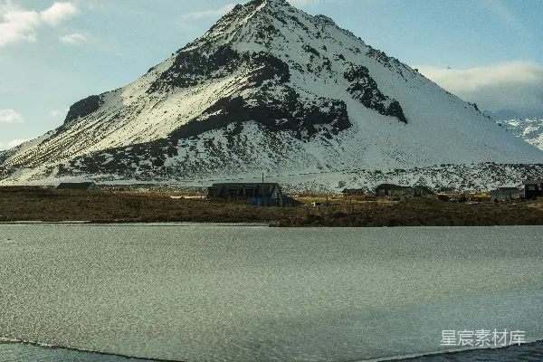 高清摄影 一座被雪覆盖的山峰，前方有一片水域。