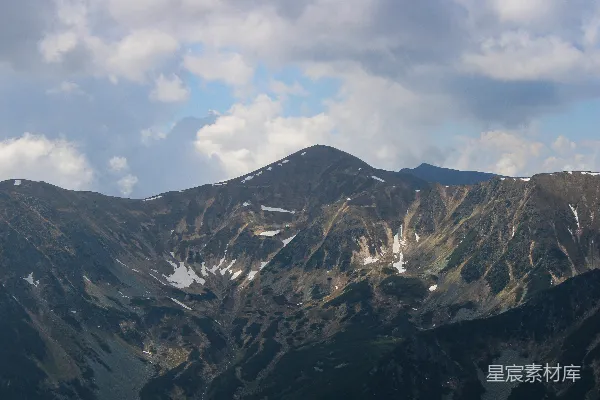 高清摄影 一座雄伟的山峰在云层密布的天空下覆盖着白雪。