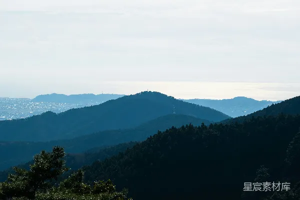 高清摄影 一片山峦景色，前景中有树木。