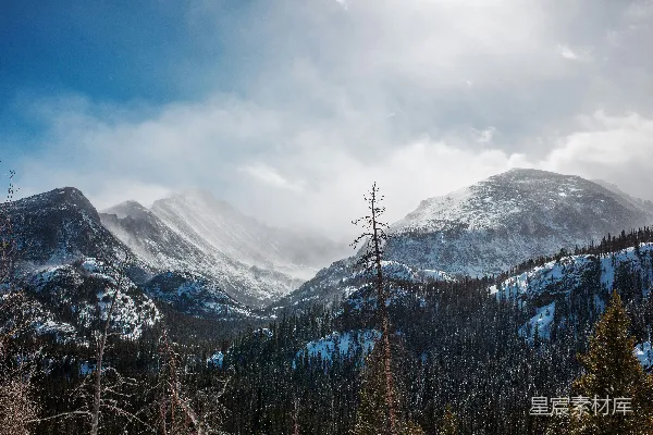 高清摄影 覆盖着积雪的山峰在戏剧性的天空下矗立。