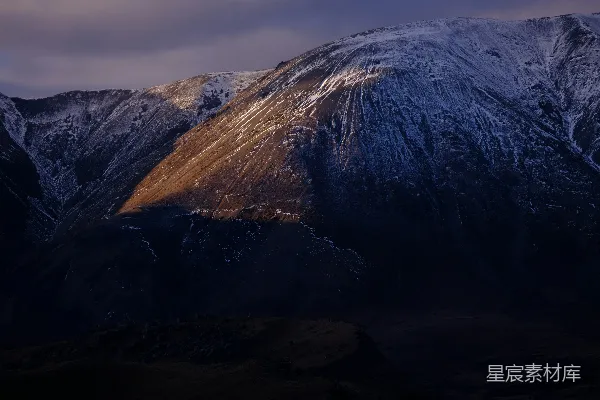 高清摄影 夕阳下被白雪覆盖的山峰，峰顶在阳光下显得格外明亮。