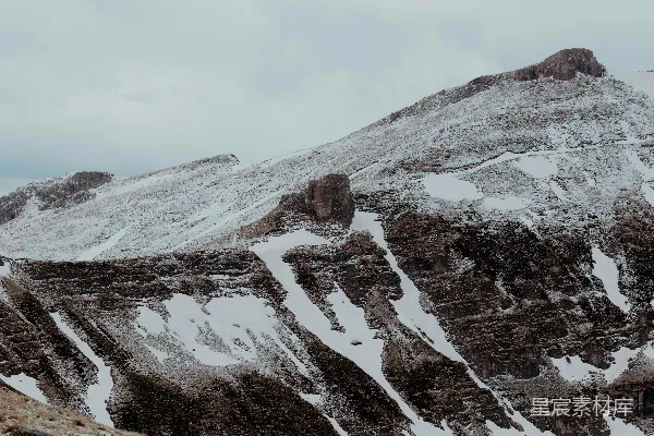 高清摄影 云层密布的天空下，覆盖着皑皑白雪的壮丽山峰。