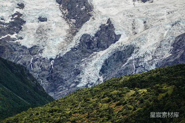 高清摄影 一座覆盖着积雪的大山紧邻一片森林。