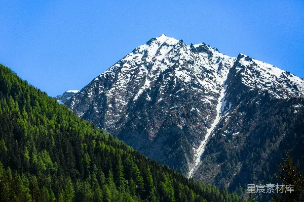 高清摄影 白雪覆盖的山峰，绿树成荫的山坡。