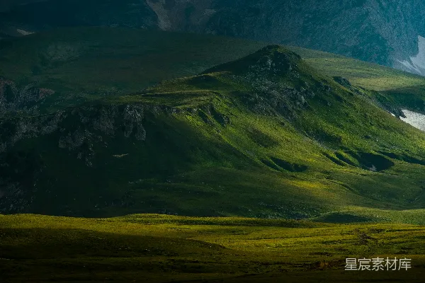 高清摄影 一片绿山，远处是白雪覆盖的山峰。