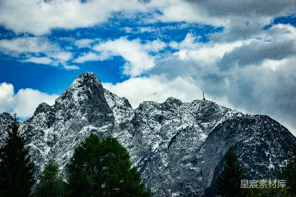 高清摄影 雪山覆盖，绿树成荫，云层低垂。