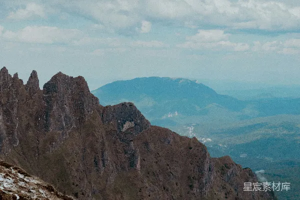 高清摄影 崎岖的山峰俯瞰着远方的山谷和多云的天空。