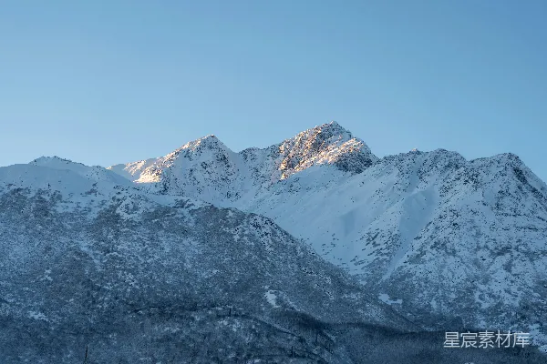 高清摄影 被积雪覆盖的山峰，背景是蓝天。