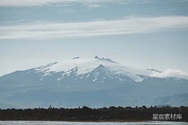 高清摄影 一座覆盖着积雪的山峦，云雾缭绕。