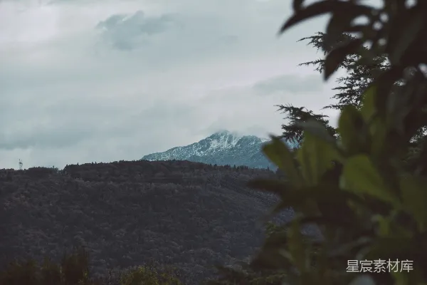 高清摄影 白天，山脚下有白云，旁边是绿树。