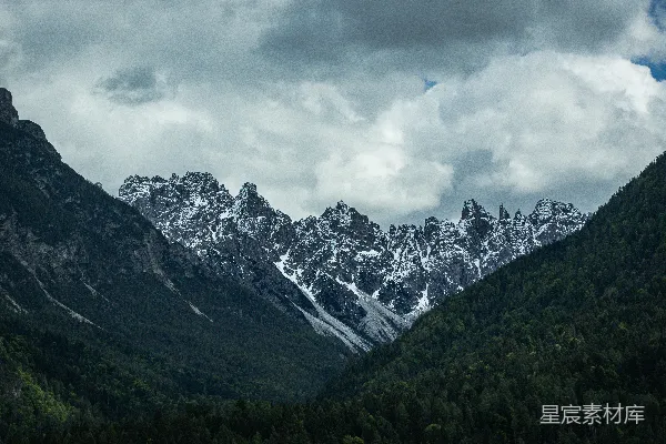 高清摄影 云层密布的天空下，山谷中的雪山。