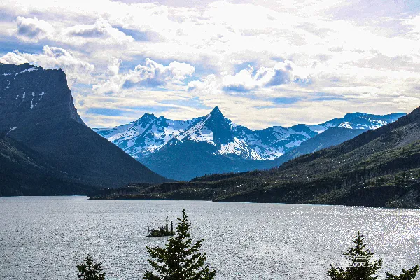 高清摄影 一座被山峦和树木环绕的湖泊，在多云的天空下。