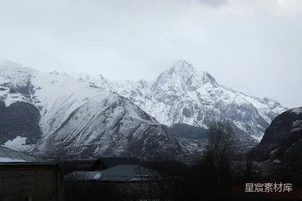高清摄影 一座被雪覆盖的山脉，前景中有房屋。