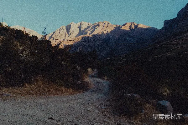 高清摄影 一条泥土路，背景中有一座山。