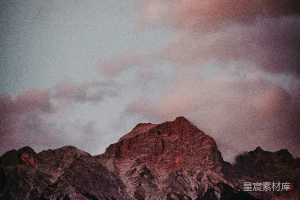 高清摄影 一座山峰，背景中有一片粉红色的天空。