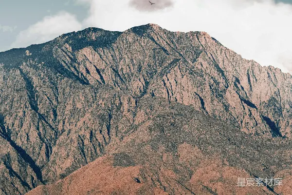 高清摄影 白天，白云飘浮在棕色岩石山下。