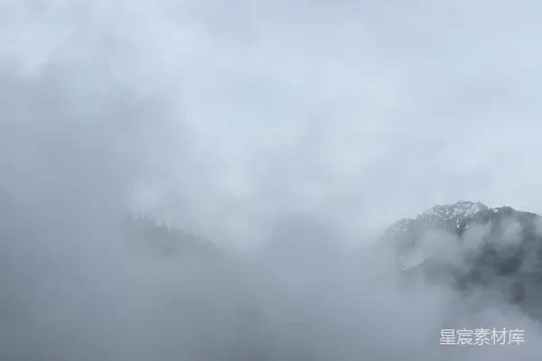 高清摄影 多云天空下，山脉被浓雾覆盖。