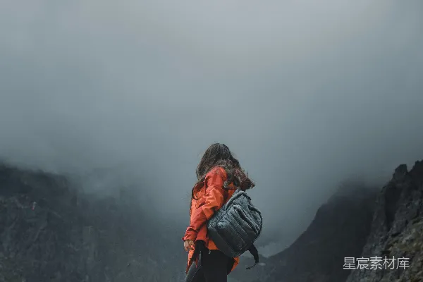 高清摄影 穿着黑色夹克，背着橙色背包的女人站在岩石形成上