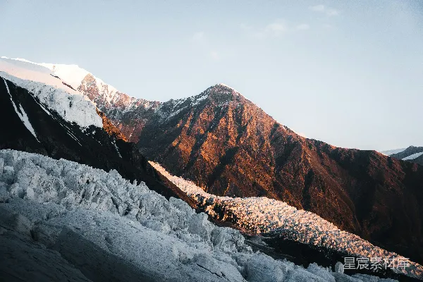 高清摄影 日出时分，雪山峰峦在温暖的光线中闪耀。