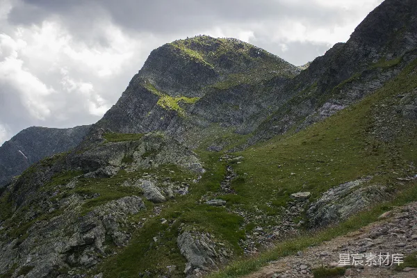 高清摄影 一座岩石山峰，山脚下有一片草地。
