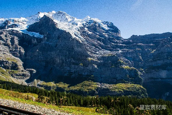 高清摄影 积雪覆盖的群山耸立在绿色的山谷之上。