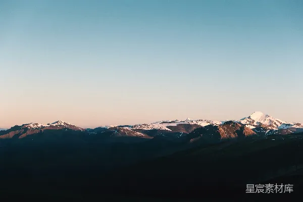 高清摄影 晴朗的天空下，日出时分的雪山覆盖着白雪。